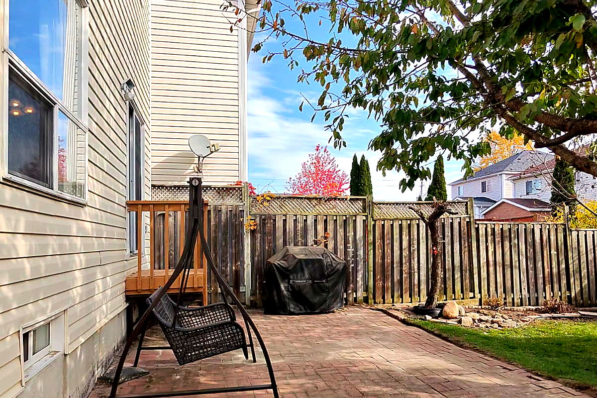 A swept brick patio and a clear lawn edge at the back of a house after a Northline backyard cleanup