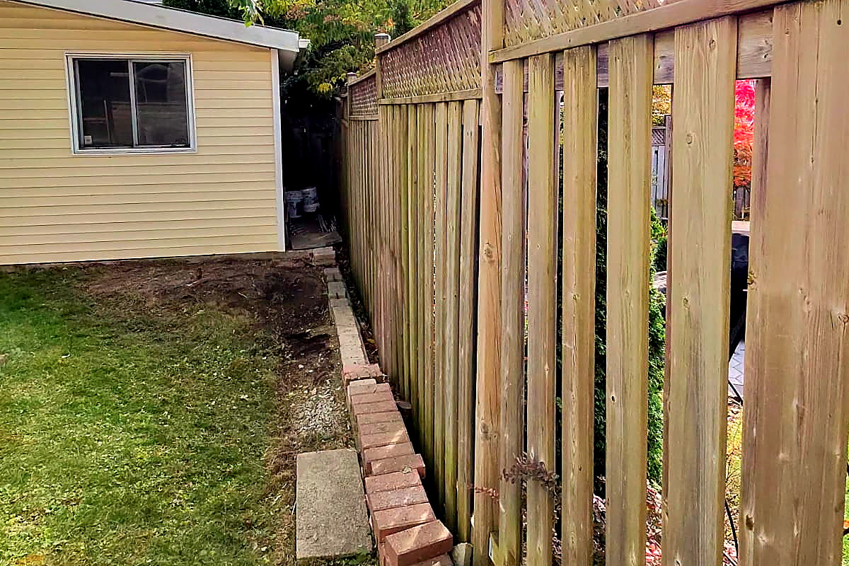 The same strip beside the shed after a Northline backyard cleanup, leaves gone and the bed cut back to clean soil