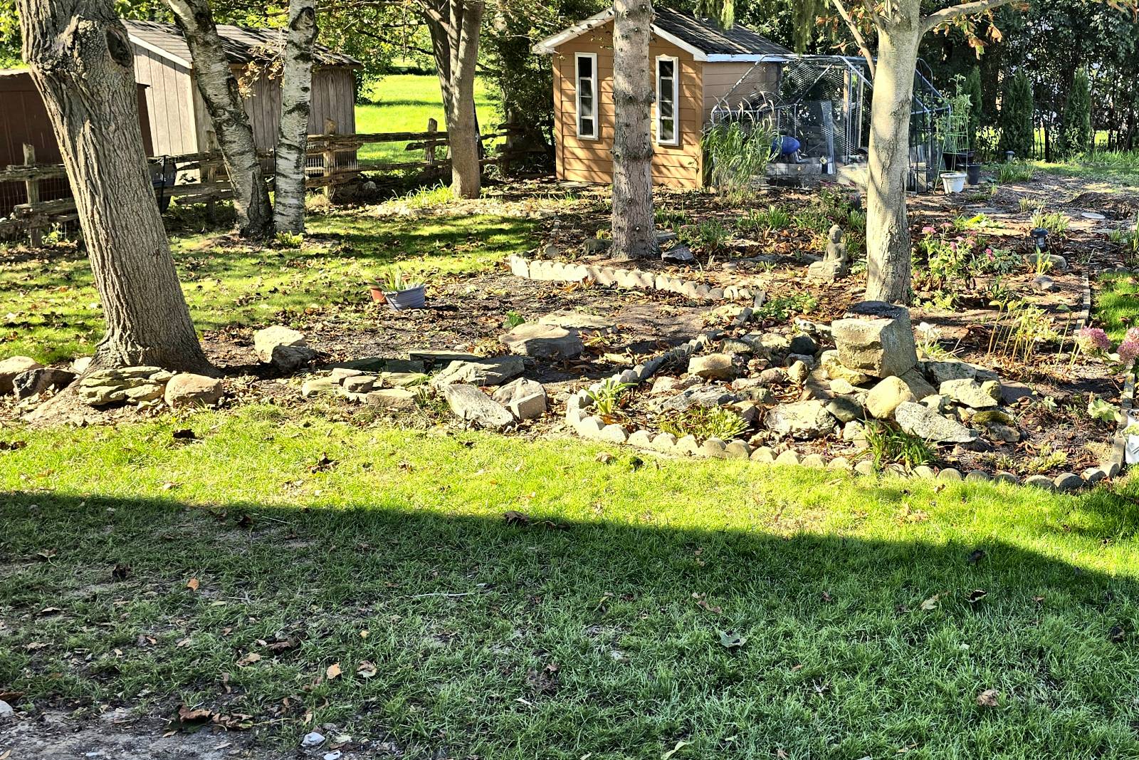 Backyard lawn and rock garden with fallen leaves before a fall cleanup
