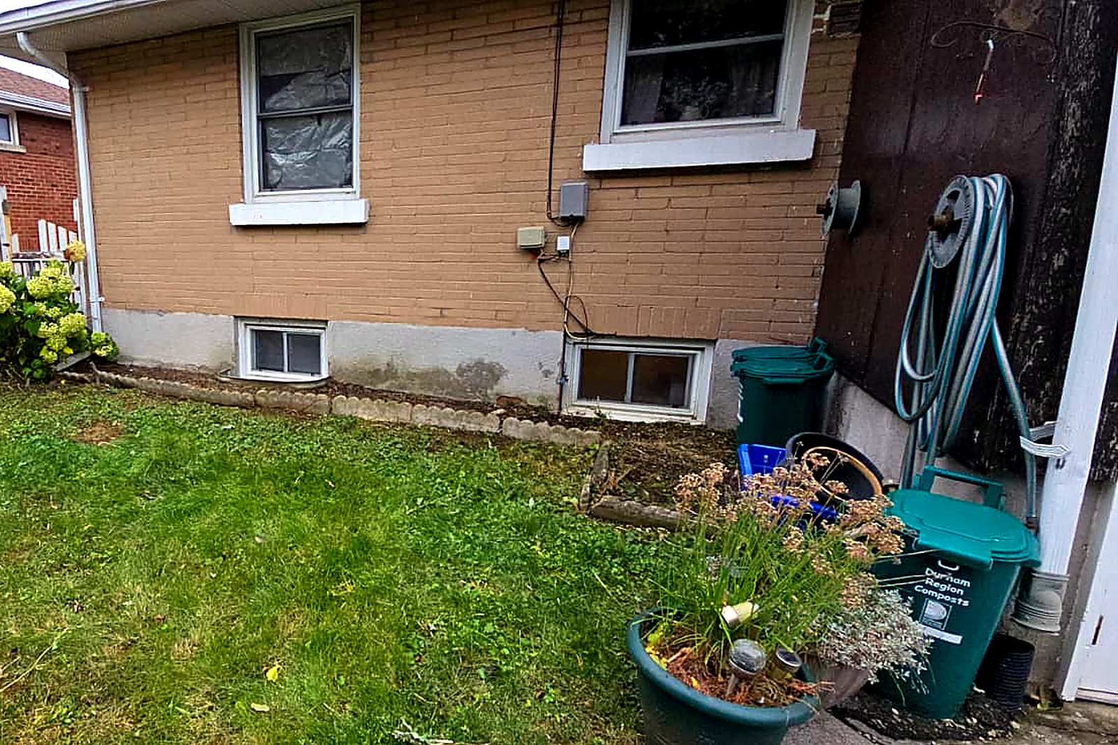 The same side foundation cleared, with the basement windows and the brick line visible again